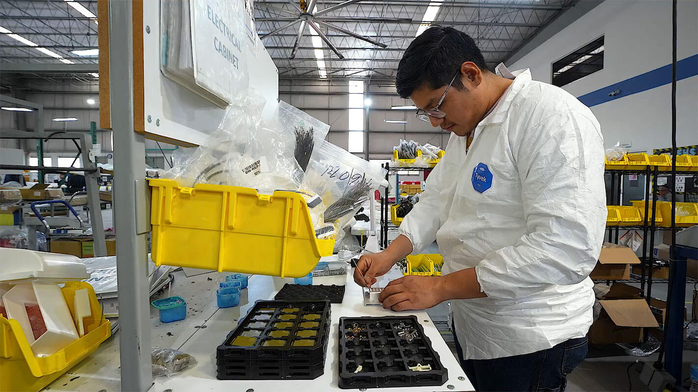 Technician kitting electronic components at a workstation in Mexico