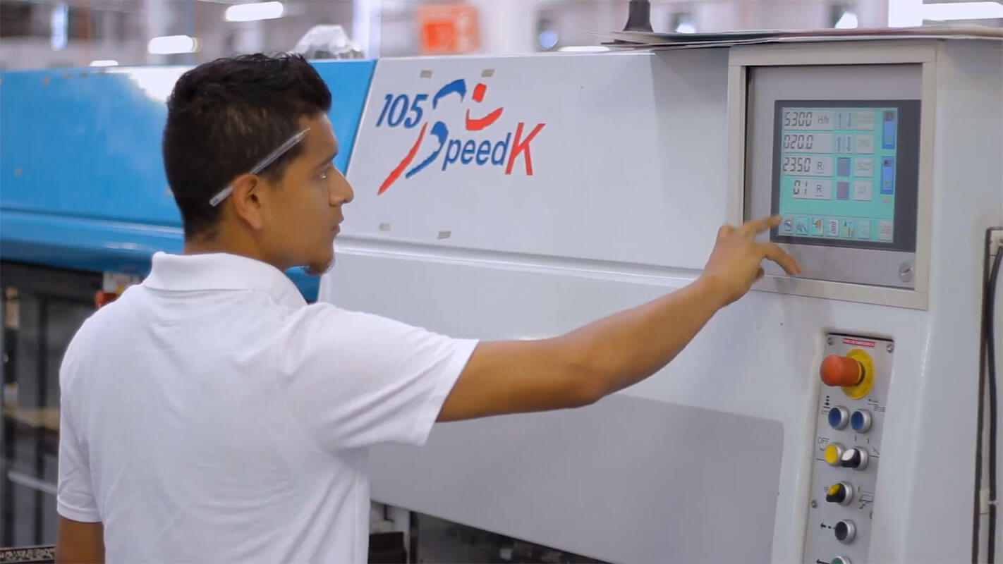 Operator setting up a printing press from its control panel at Shelmex in Mexico